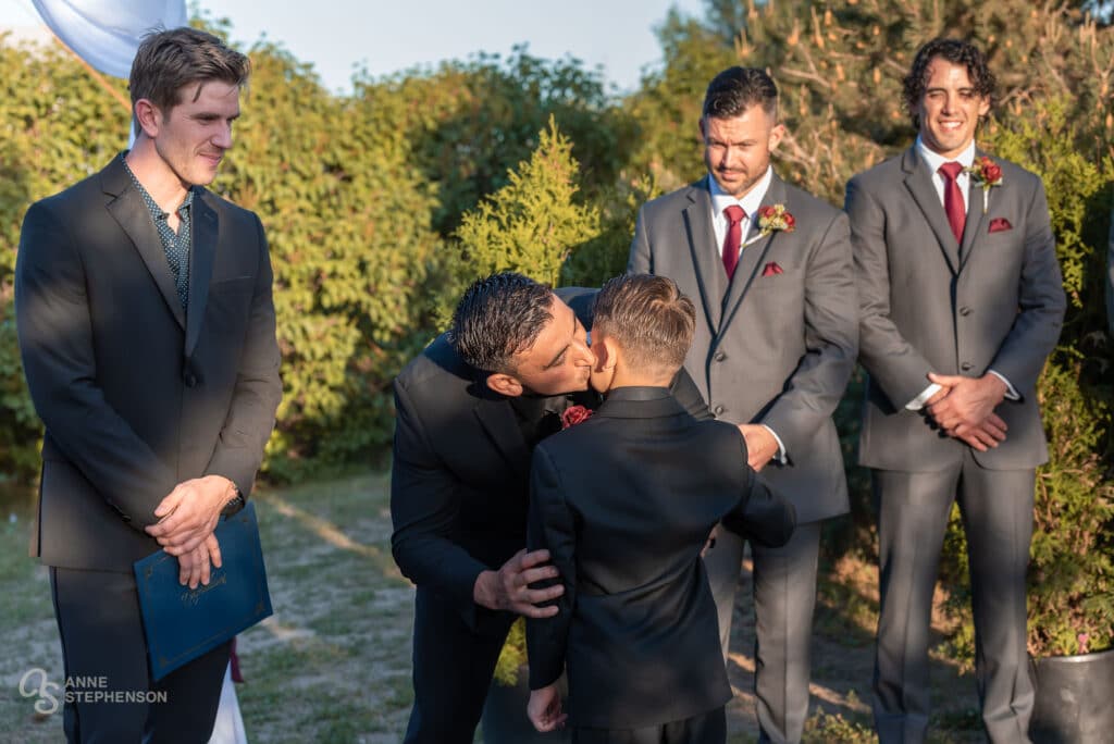 The groom kisses his son's cheek after walking down the aisle.