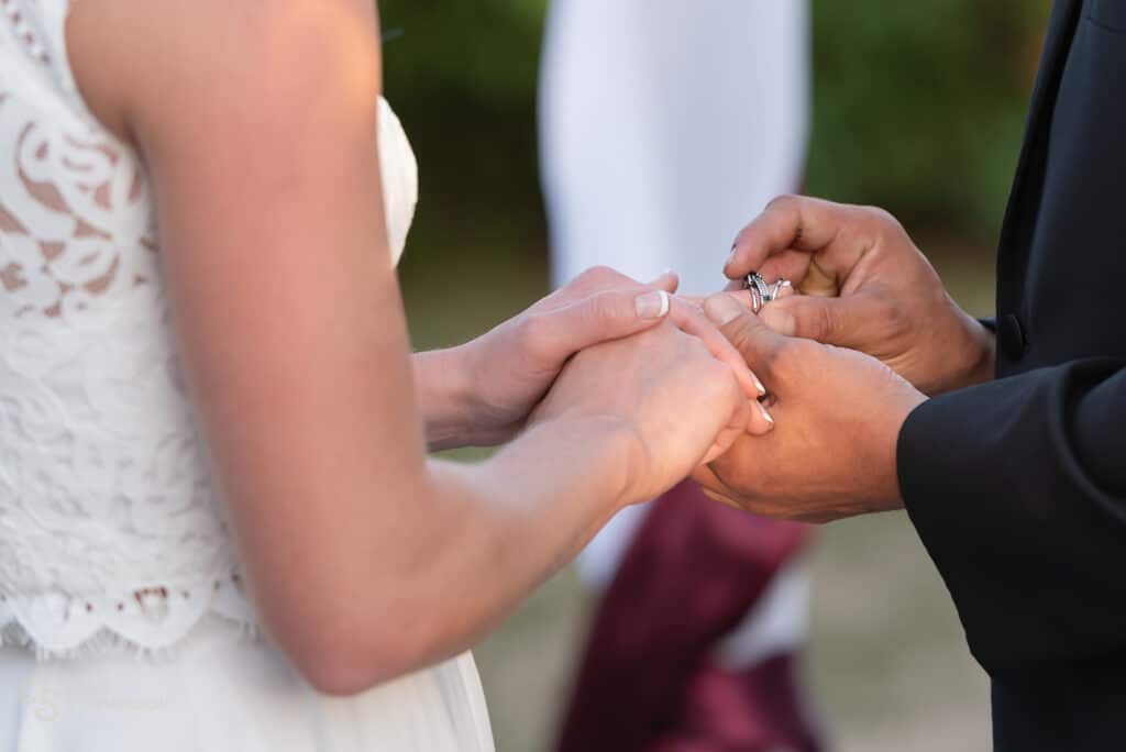 Close up of the groom placing the ring on the bride's finger.