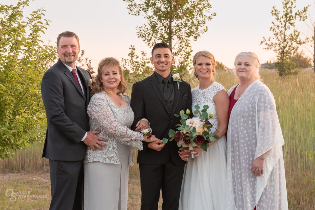 The father and mother of the groom, along with the mother of the bride, pose with the wedded couple.