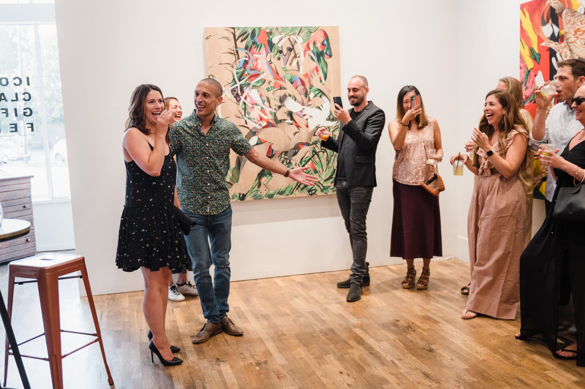 A woman enters an art gallery and realizes the group of people there are holding a surprise party in her honor.