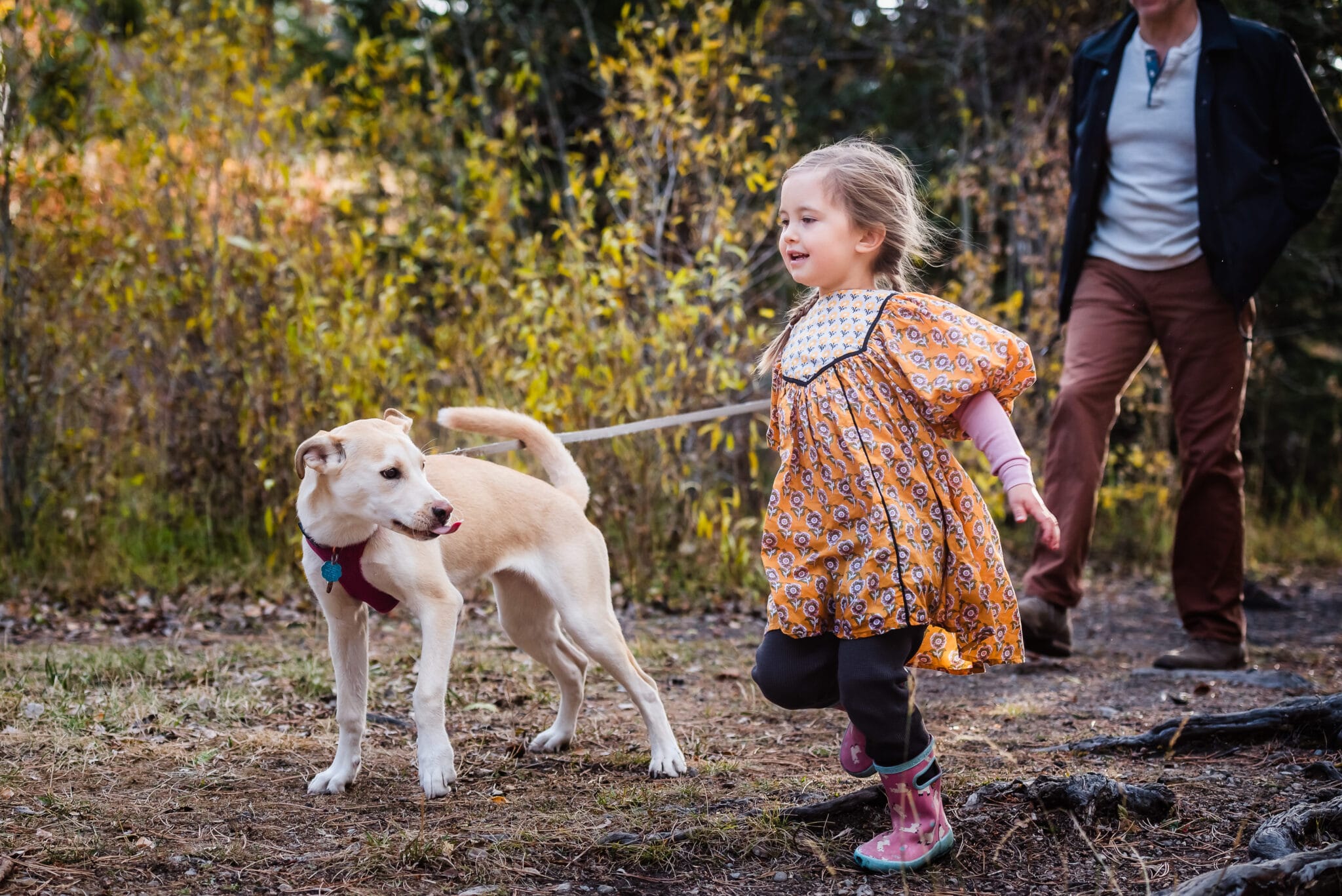 A young girl walks along with her dog during a family portrait session.