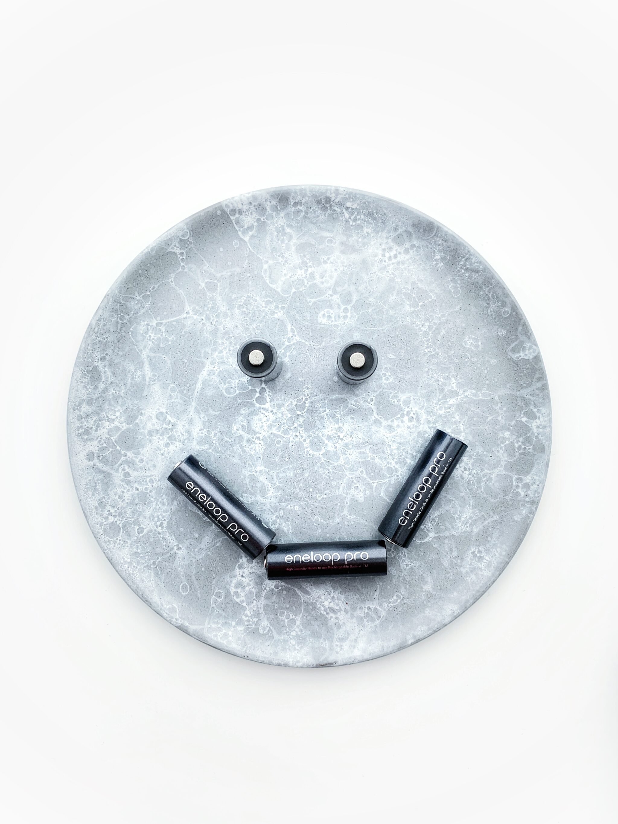 An overhead view of eco-friendly photography batteries that are positioned to look like a smiling face.