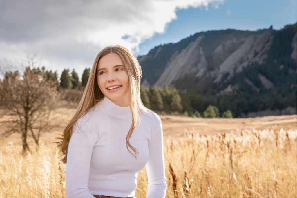 A young woman at Chautauqua Park with the scenic Flat Irons behind her.
