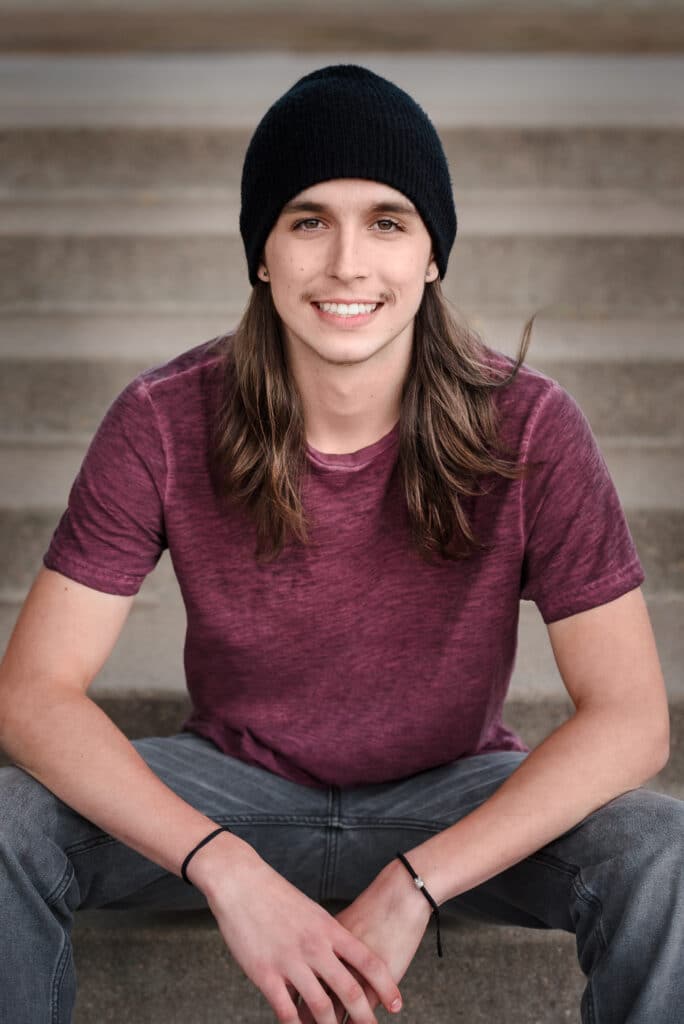 Young man sitting on stairs during his senior photo session at City Park, Denver.