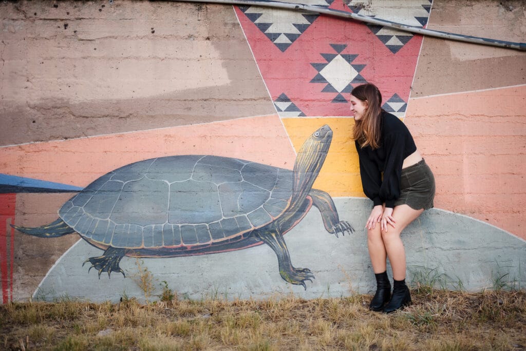 A young woman looks at a turtle painted on an artistic wall in downtown Denver.