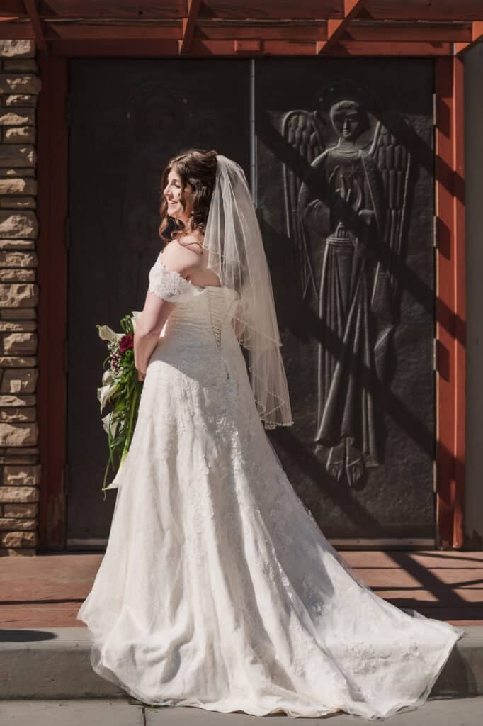 A bride turns to look over her shoulder in a striking portrait in front of the metal doors etched with angels at the Danforth Chapel, CSU.