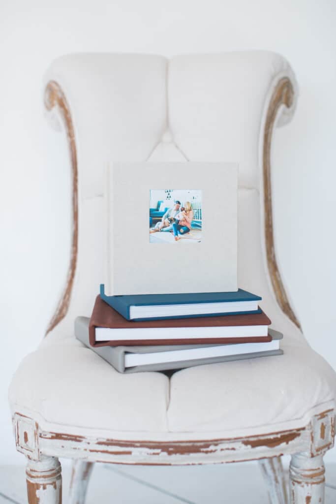 A stack of linen albums on a white chair.