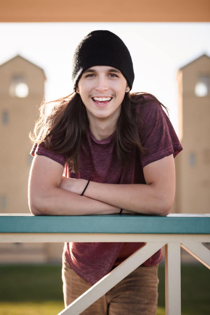 A young man in a cap poses for a senior session at City park.