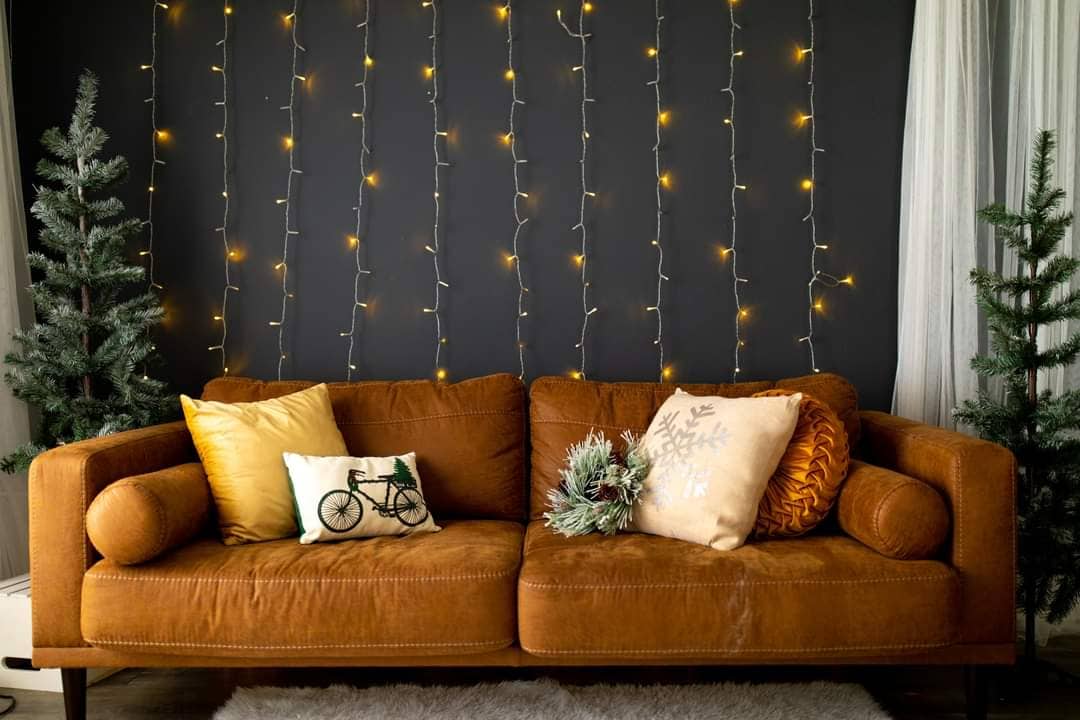 The couch set at Studio Avenue, Loveland features a two-cushion couch in cinnamon brown and string lights in the background.