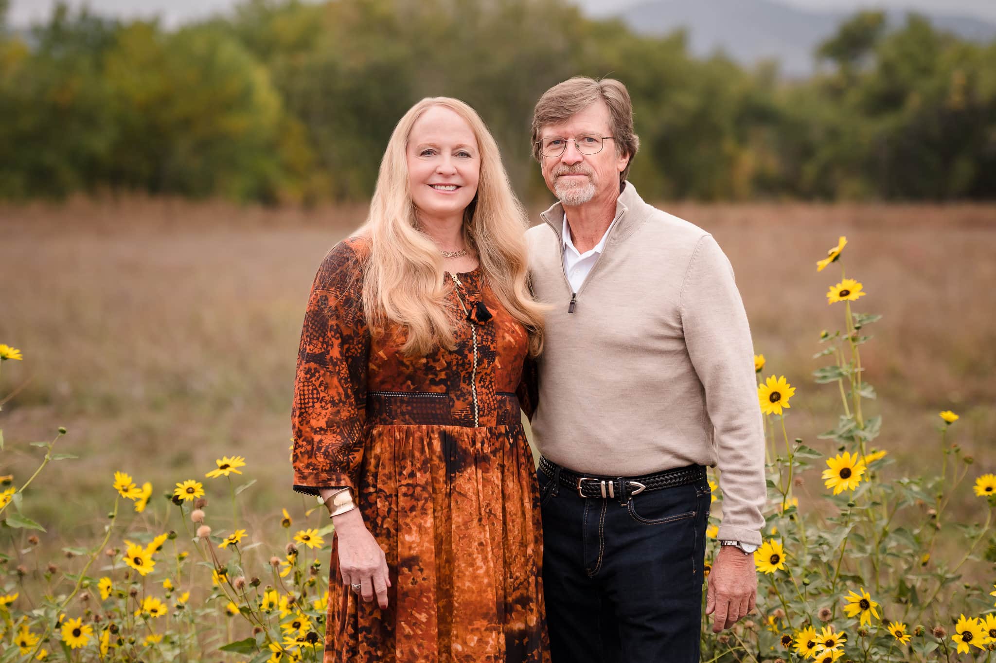 A man and woman celebrating their 40th anniversary pose for a photo amid the wild sunflowers outside of Sweet Heart Winery in Loveland, CO.