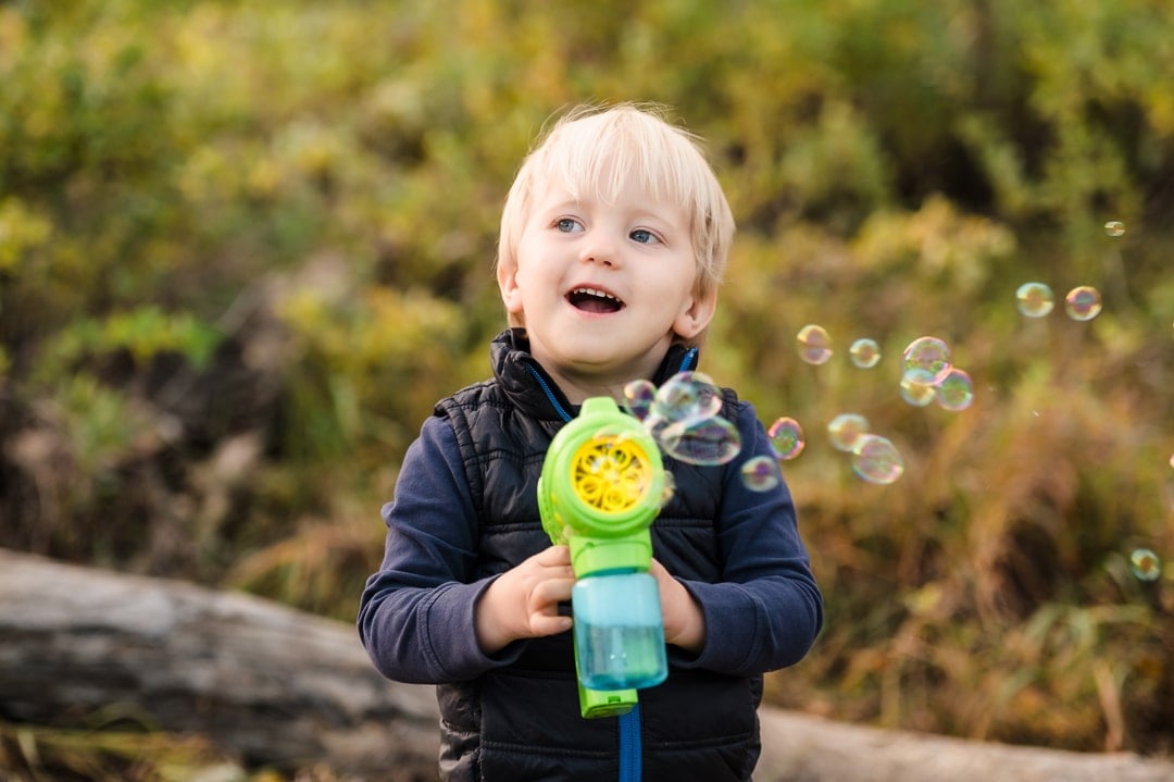 A young boy watches in amazement as a machine rapidly creates bubbles.