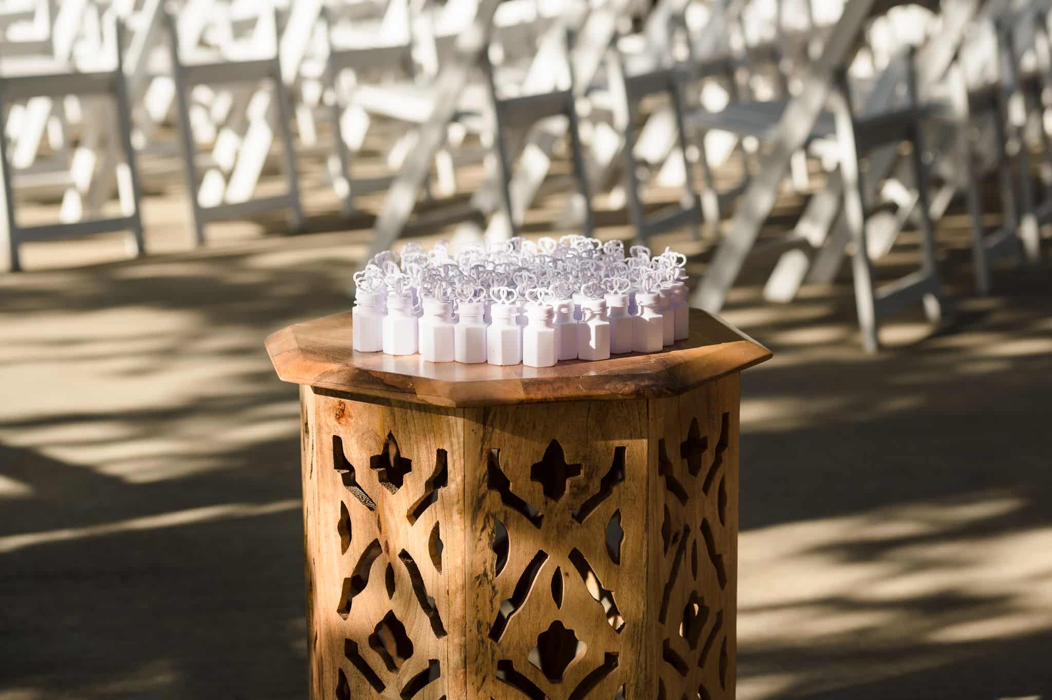 Pretty white decorative bubbles on a carved wood table placed in front of the guest's chairs at a wedding.