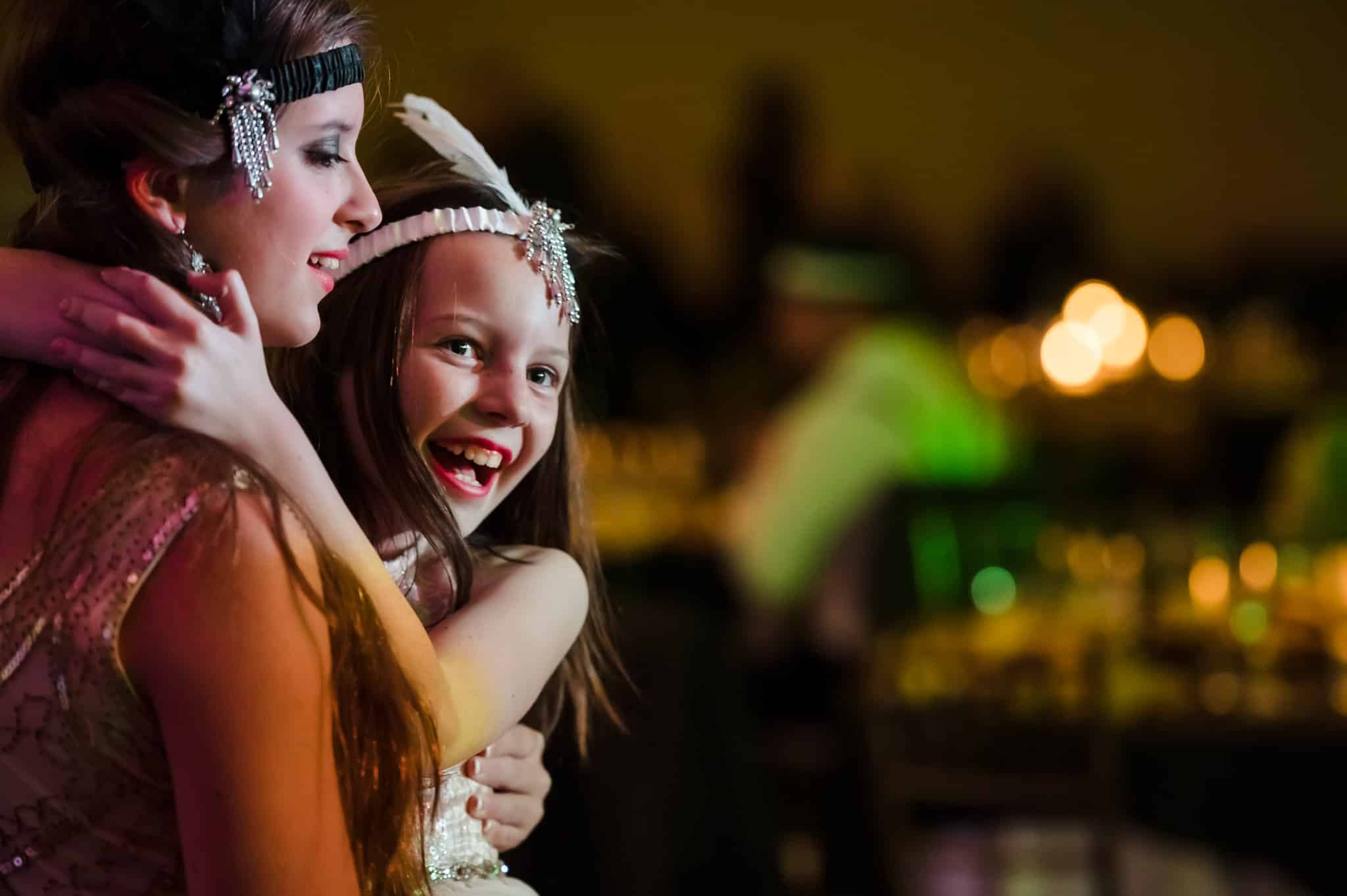 A teenage girl lifts her younger sister at a 1920s costume party.