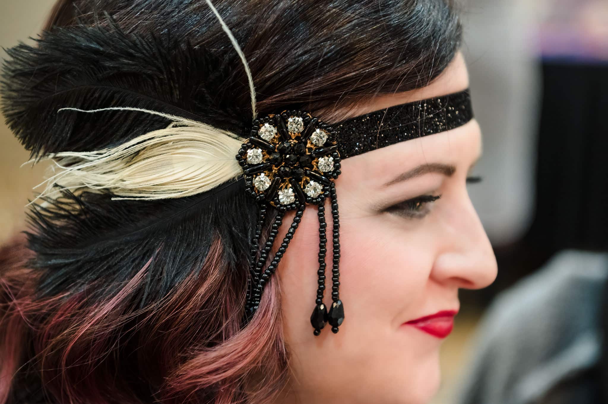 Close up of a 1920s style headband with beads and feather worn by a guest at a surprise 40th birthday Great Gatsby themed party.