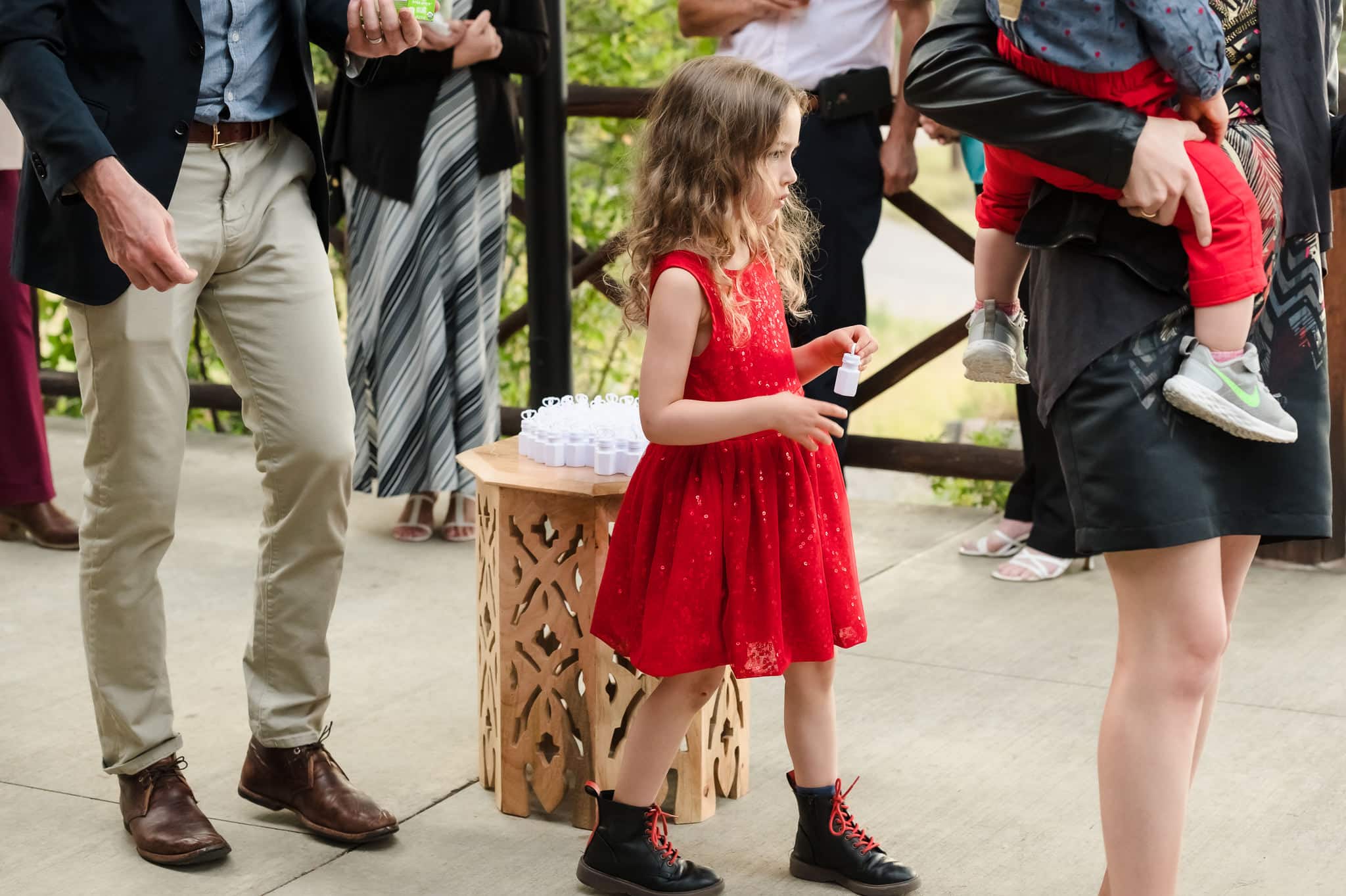 A young girl selects a bottle of bubbles that are in a white container with a wand shaped in a heart at the end of the stick.