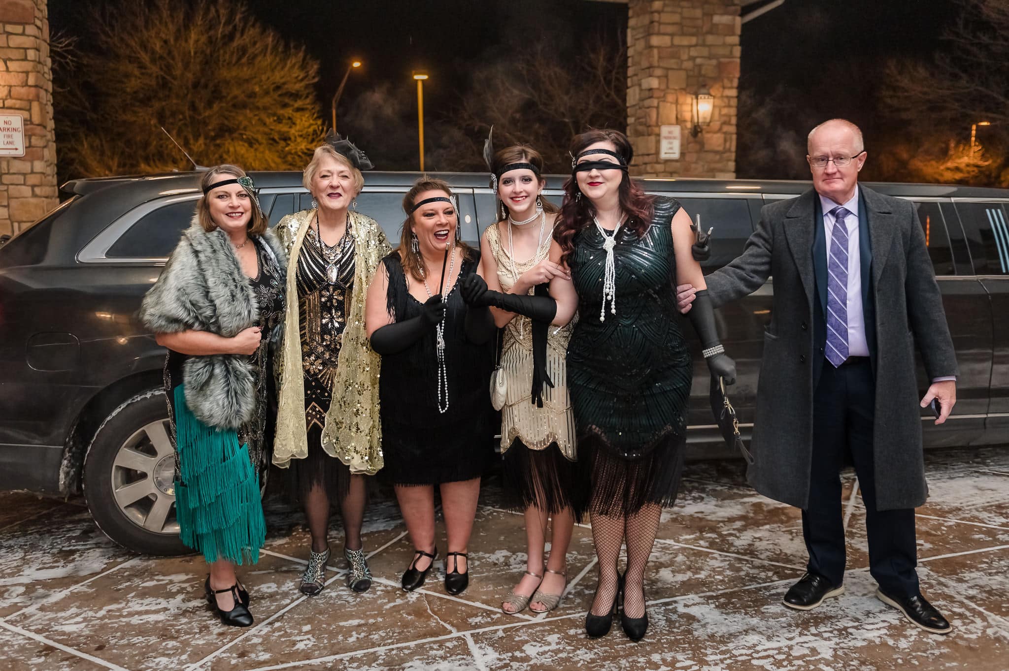 Guests dressed in 1920s attire for a Great Gatsby party arrive via a limousine. 