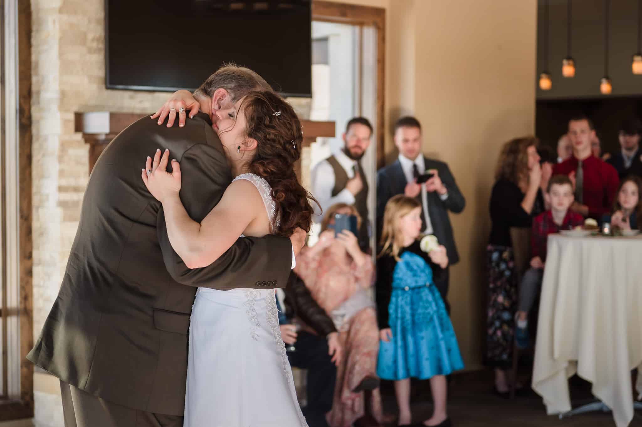 The bride gives her father an emotional hug as the crowd looks on following their daddy daughter dance