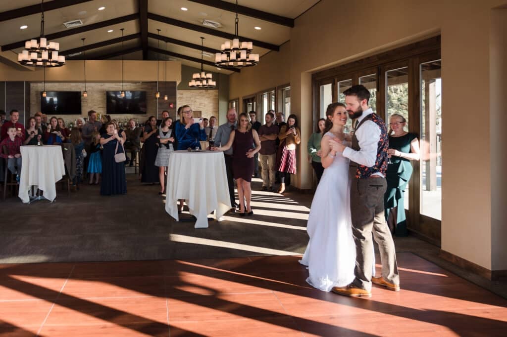 The bride and groom perform a choreographed first dance as their guest look on in the sunny room.