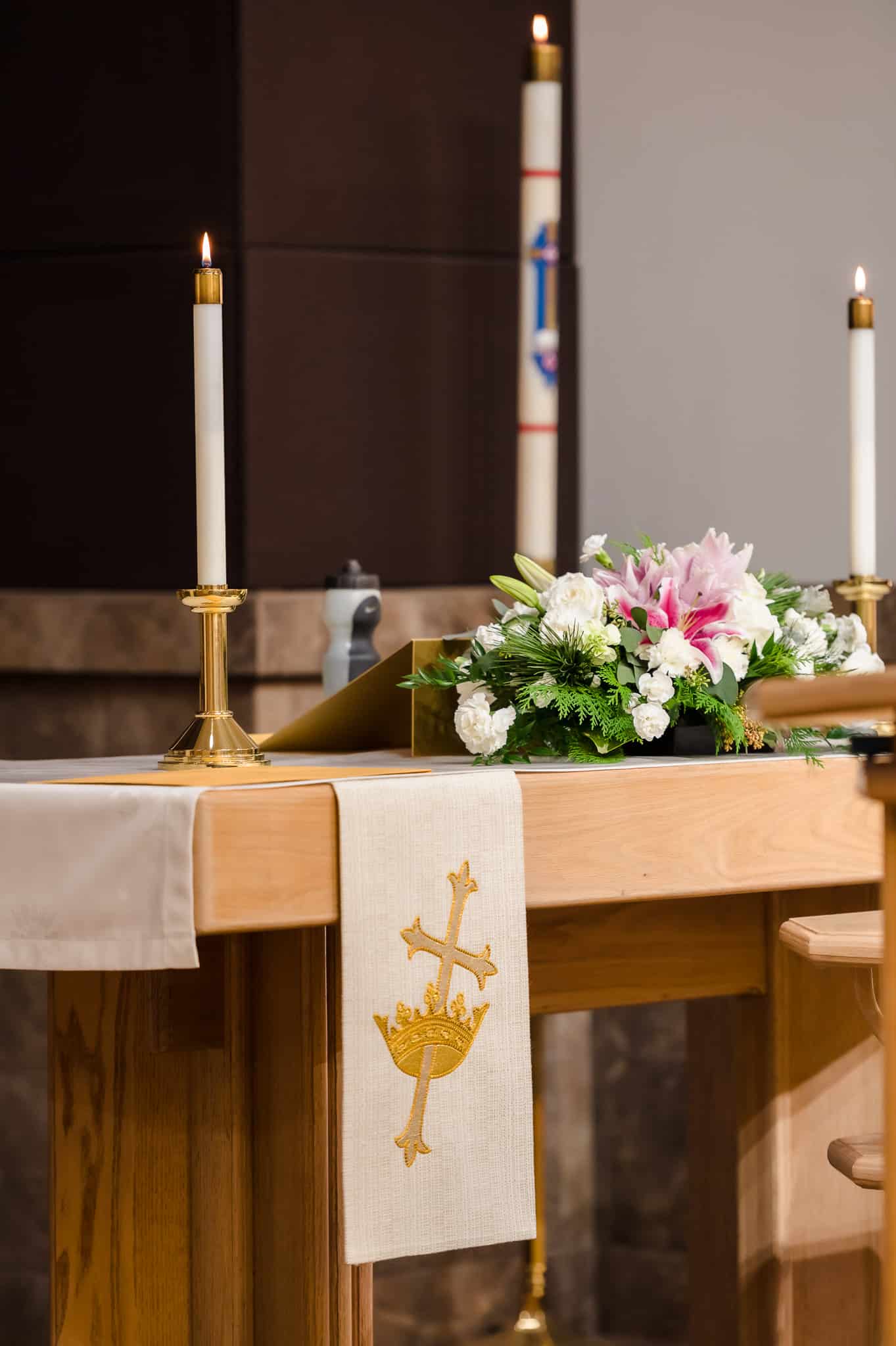 The altar of Risen Savior Lutheran church with a floral arrangement and burning candles.