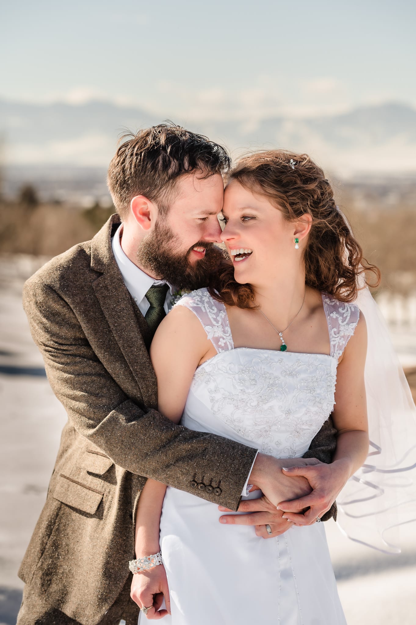 A bride and groom playfully touch noses during their photo session in the winter snow.