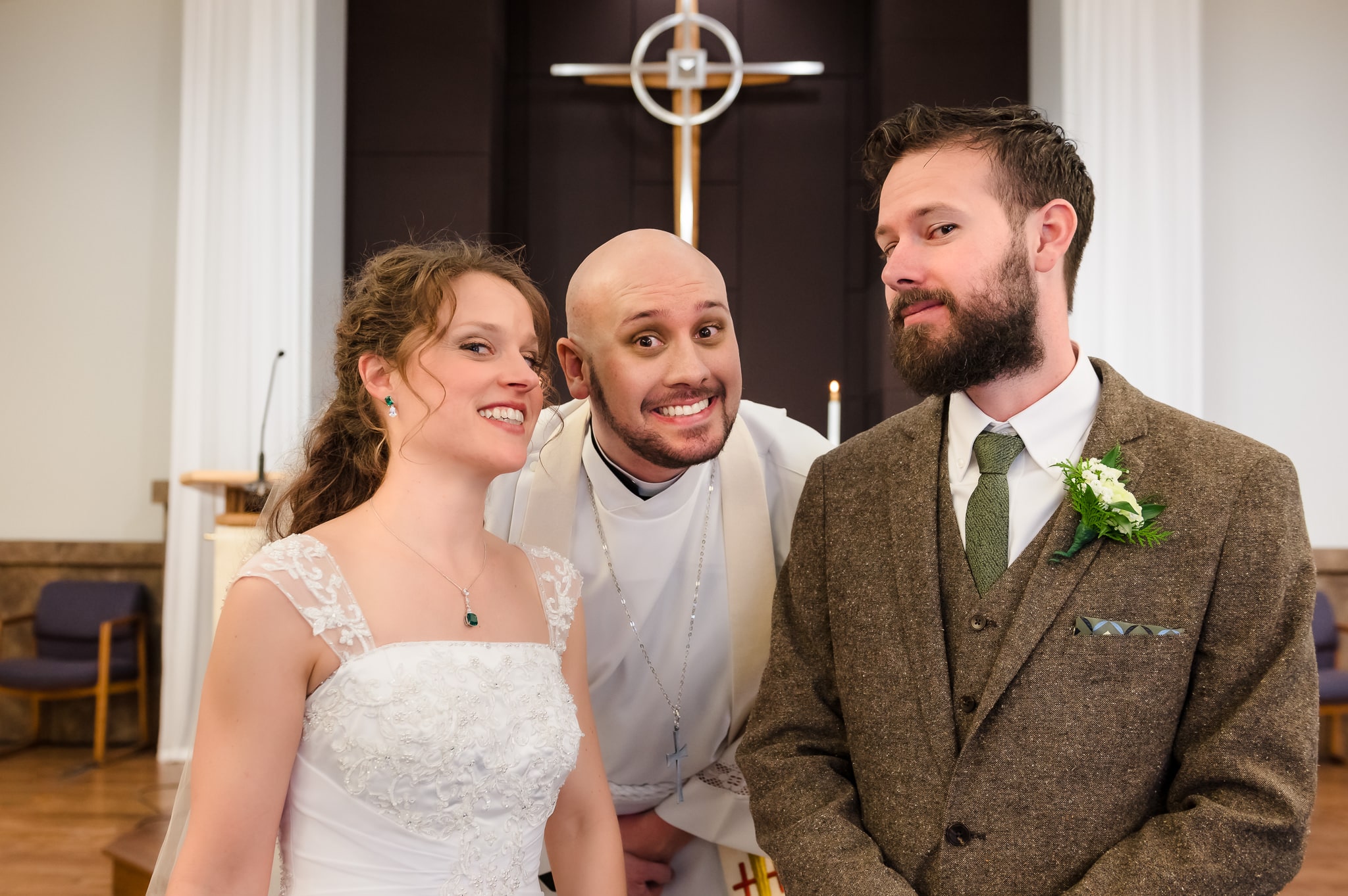 The brother of the groom and acting officiant make faces as he stands between the couple.