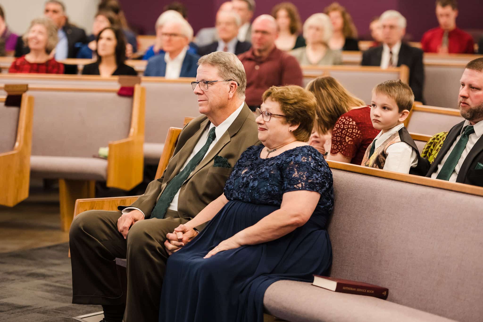 The parents of the bride seated with the congregation during their daughter's wedding.