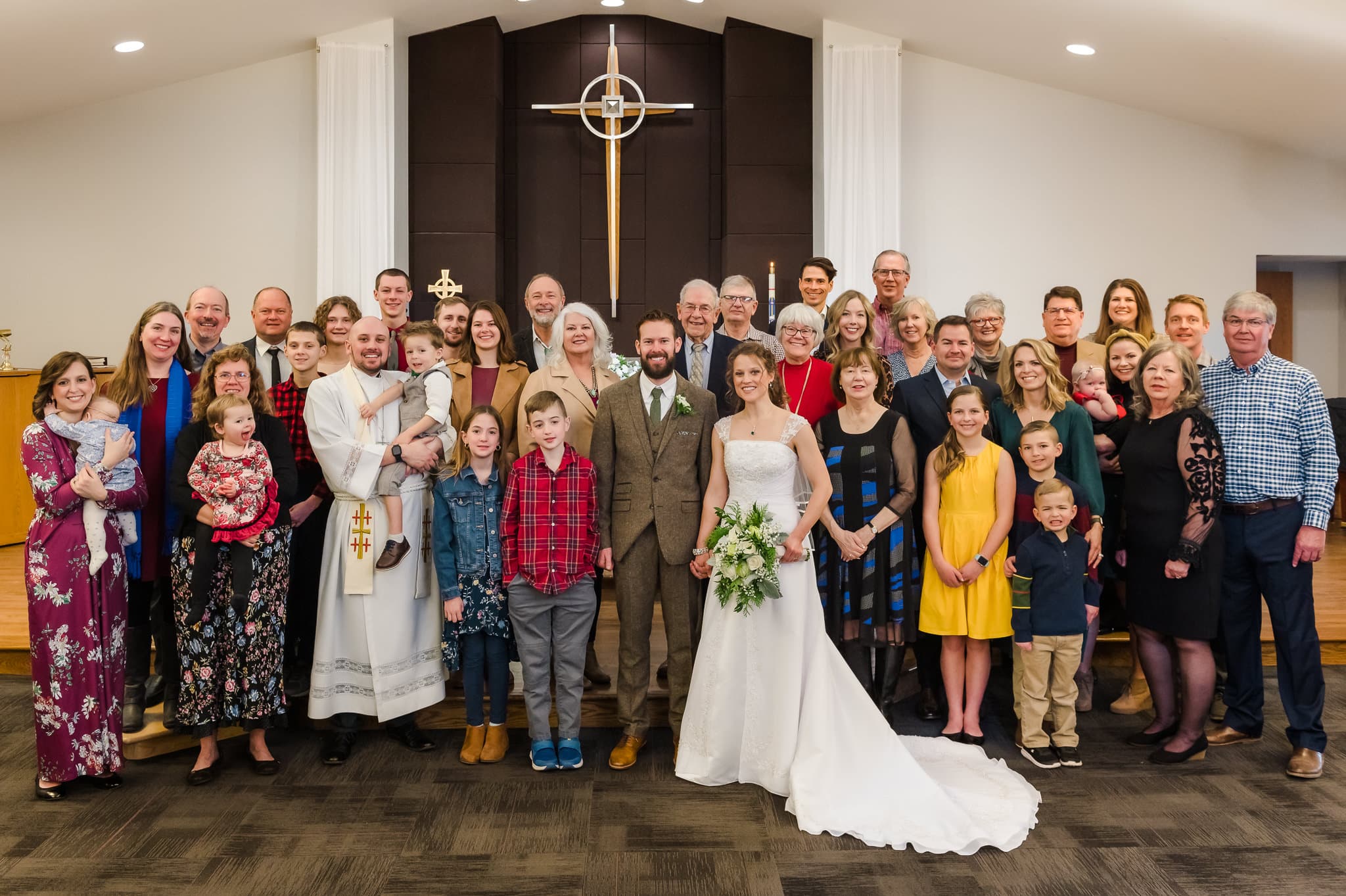 The bride and groom at the front of the church surrounded by both sides of their families for a large group photo.