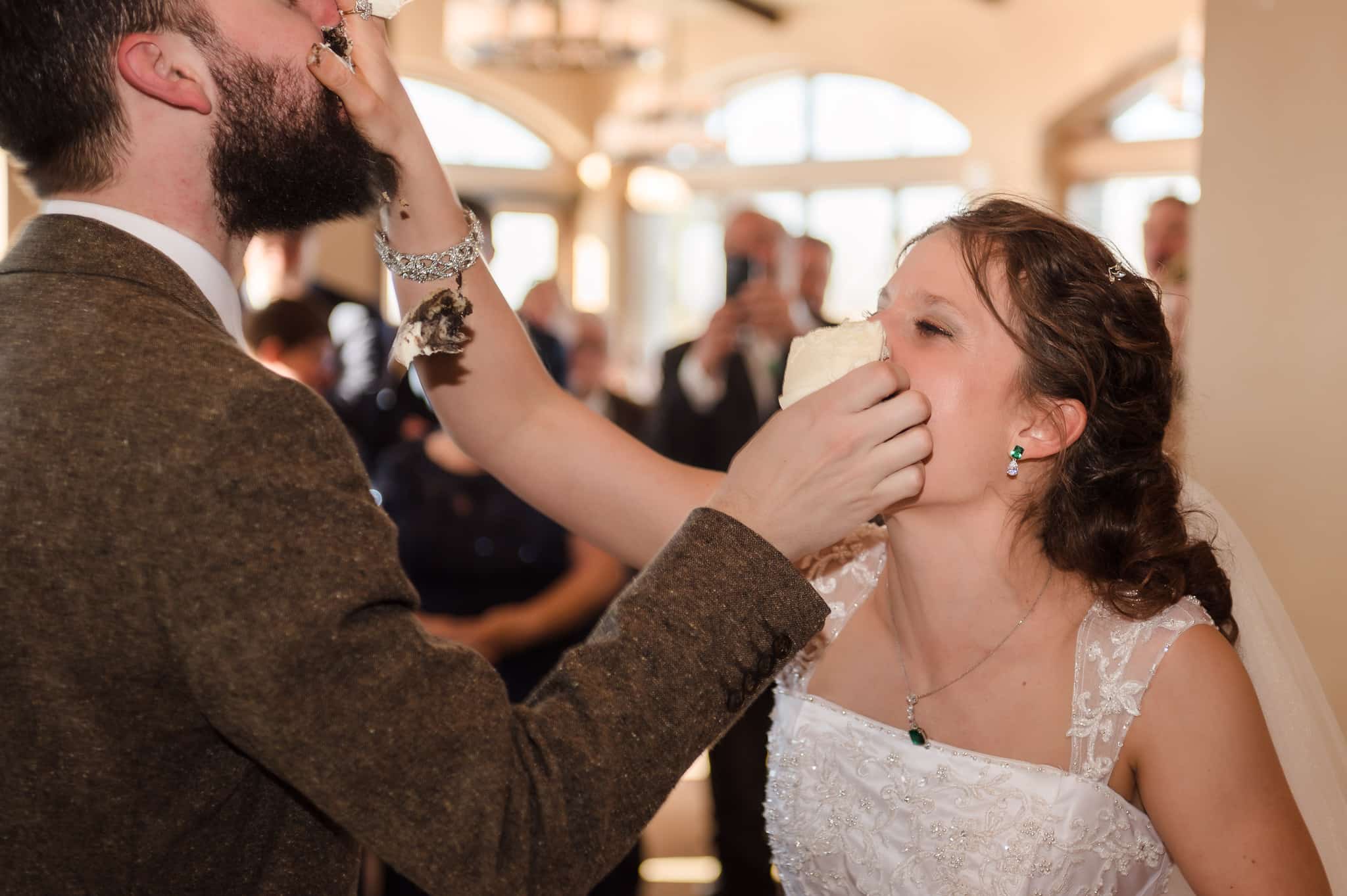 The bride and groom feed each other cake and in the process smash the pieces into each others faces.