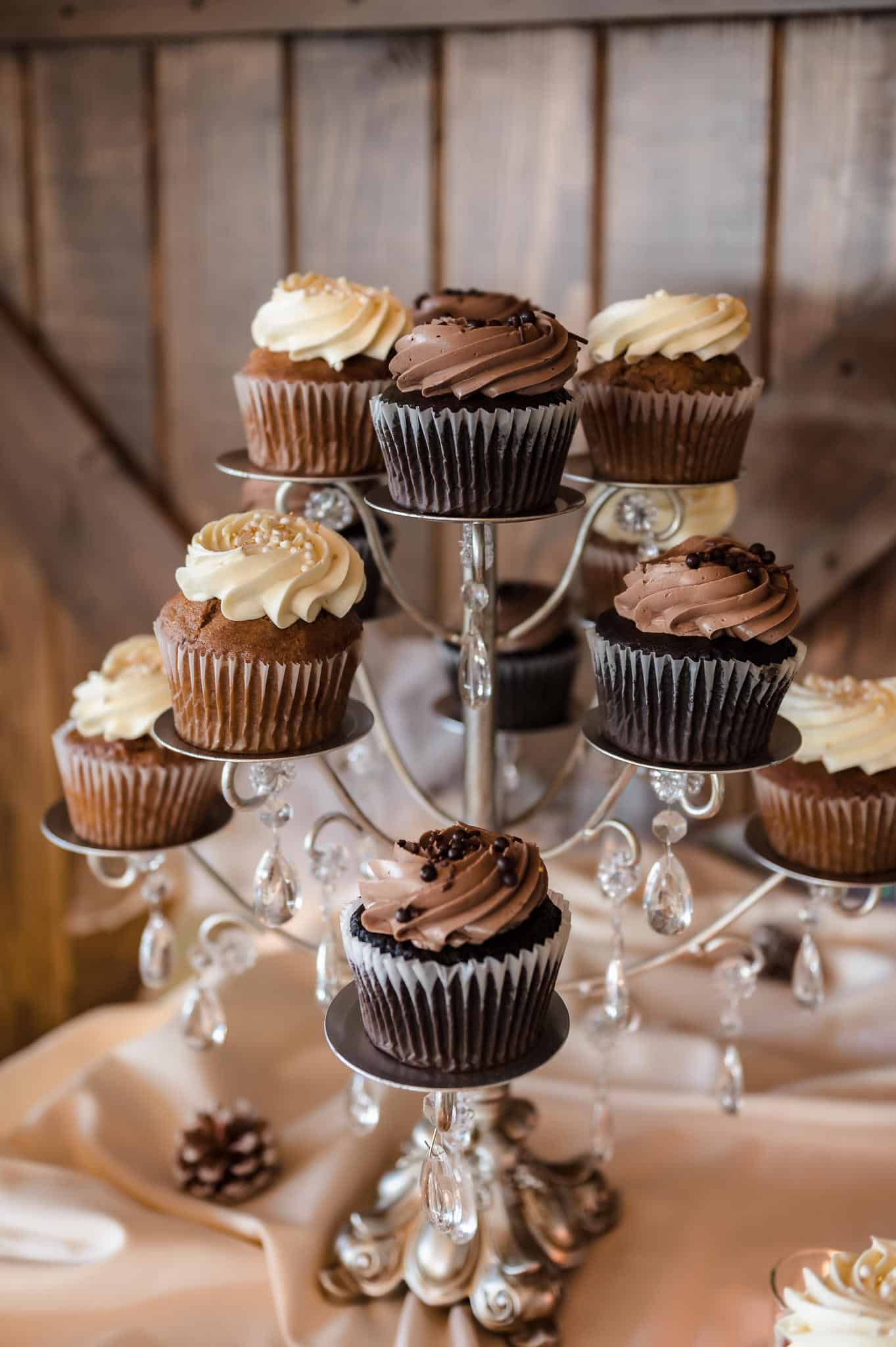 Close up of vanilla and chocolate frosted cupcakes at a wedding on the dessert table.