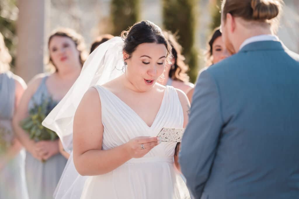 The bride looks down at her slip of paper that contains her wedding vows.