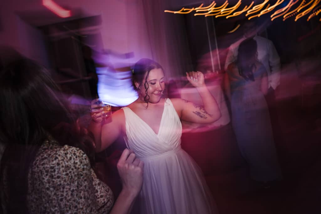 The bride enjoys celebrating her wedding by dancing amid a colorful light show.