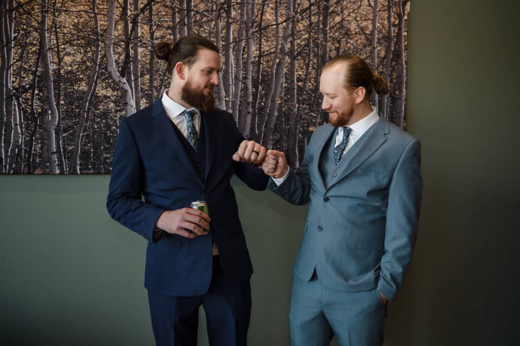 The groom and best man give each other fist bumps in the waiting room before the wedding.