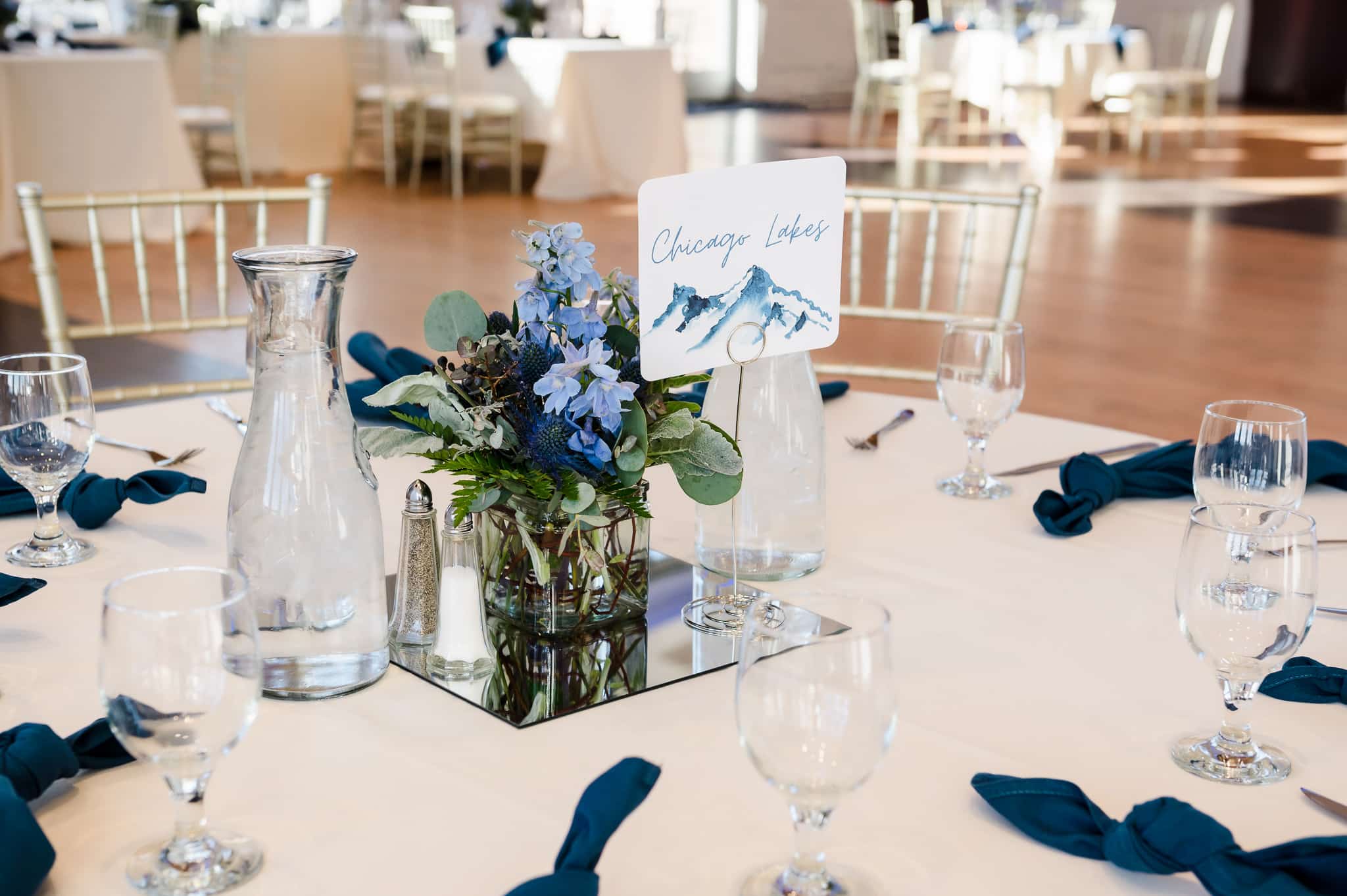 Close up of a wedding table that includes a card labeled "Chicago Lakes" one of many sites where the bride and groom hiked. They used locations instead of numbers to identify where guests should be seated.