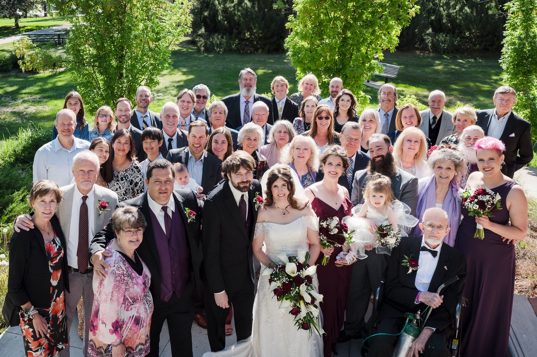 A large wedding party after the ceremony illustrates that how to get the best large group photos often involves the photographer shooting from a step ladder.
