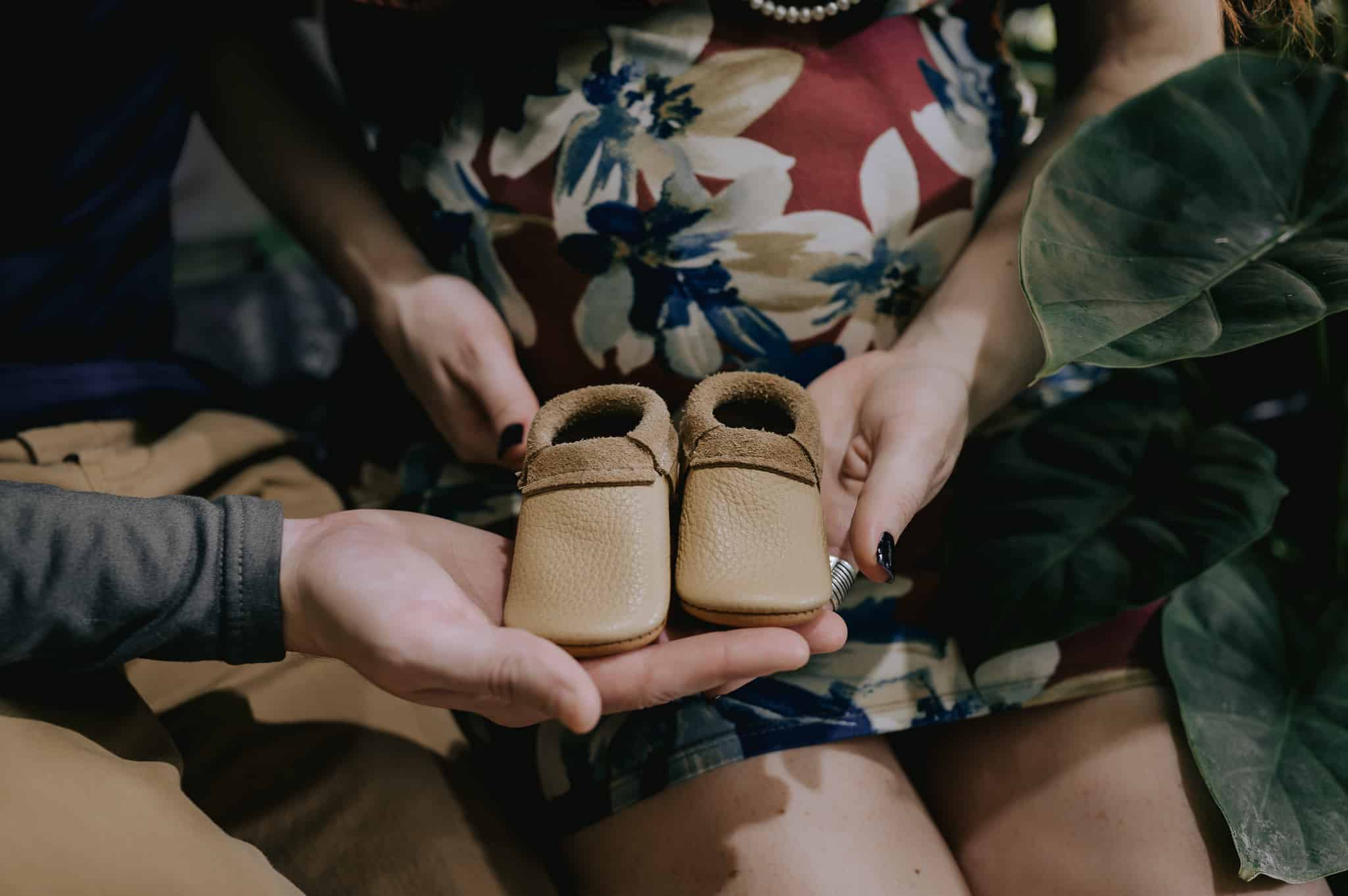 Close up of tiny baby booties during a jungle maternity photo session.