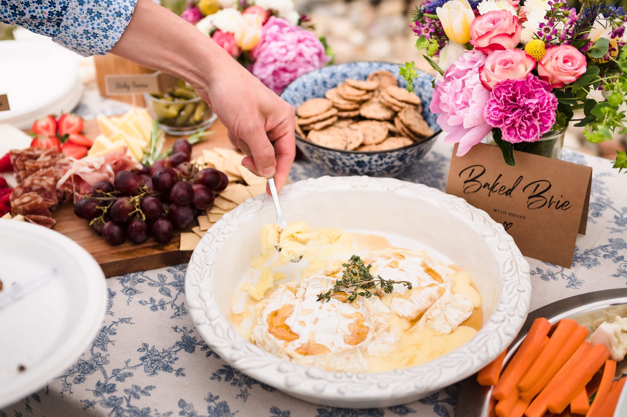 A man serves up baked brie at this outdoor going away party that combined the natural environment with touches of elegance.