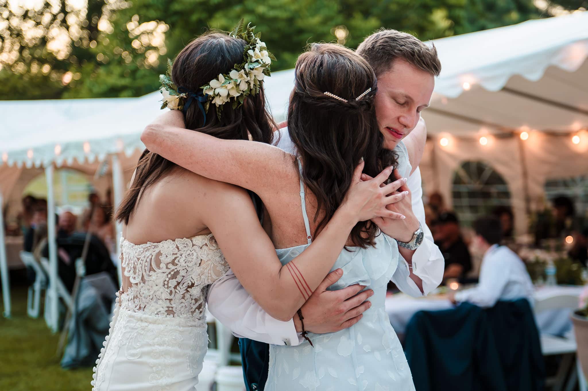 The groom hugs his mom and his bride following the mother and son dance.