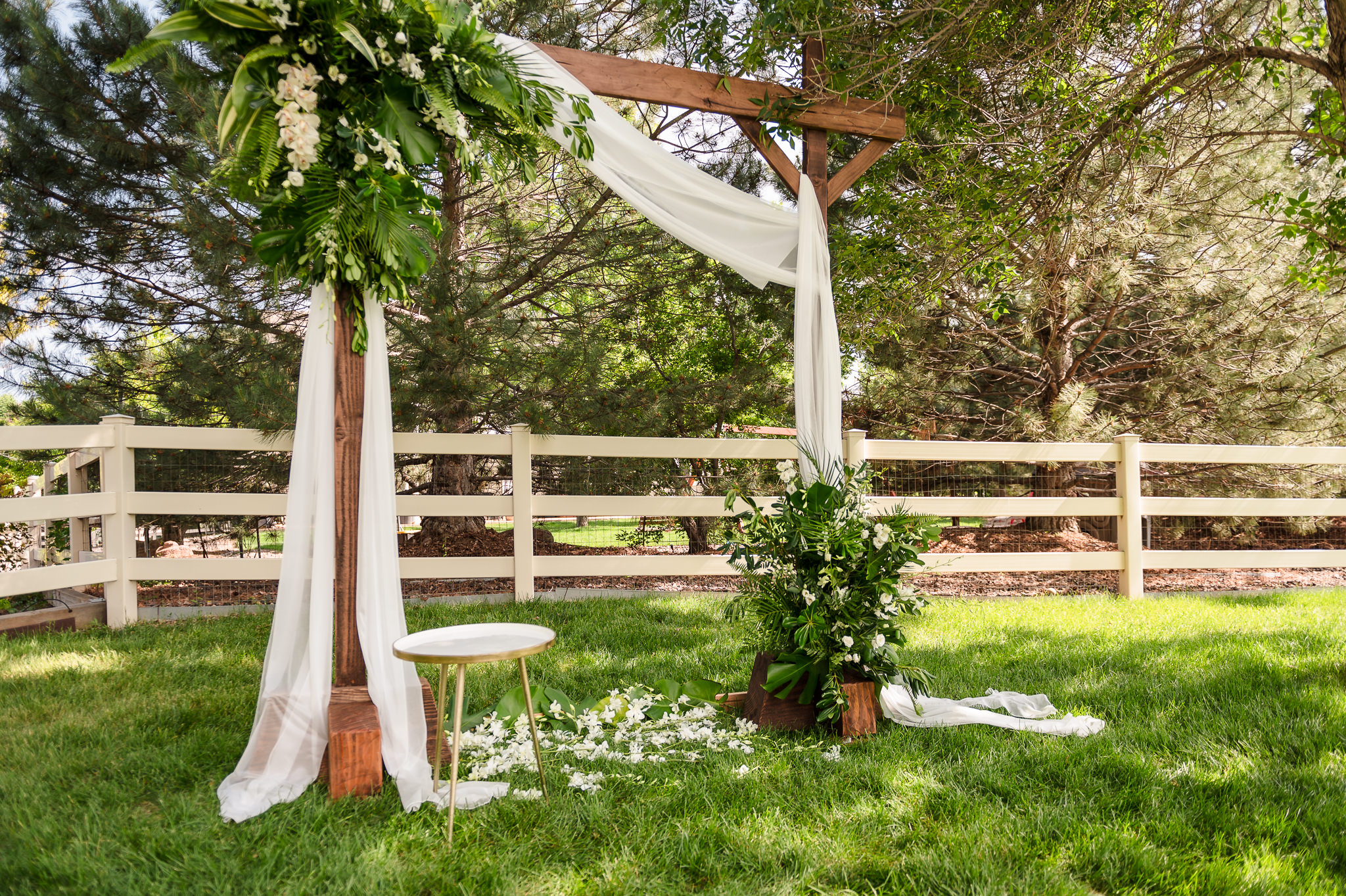 An outdoor wedding arbor decorated with Hawaiian flowers and a cream color drape over wooden frame.