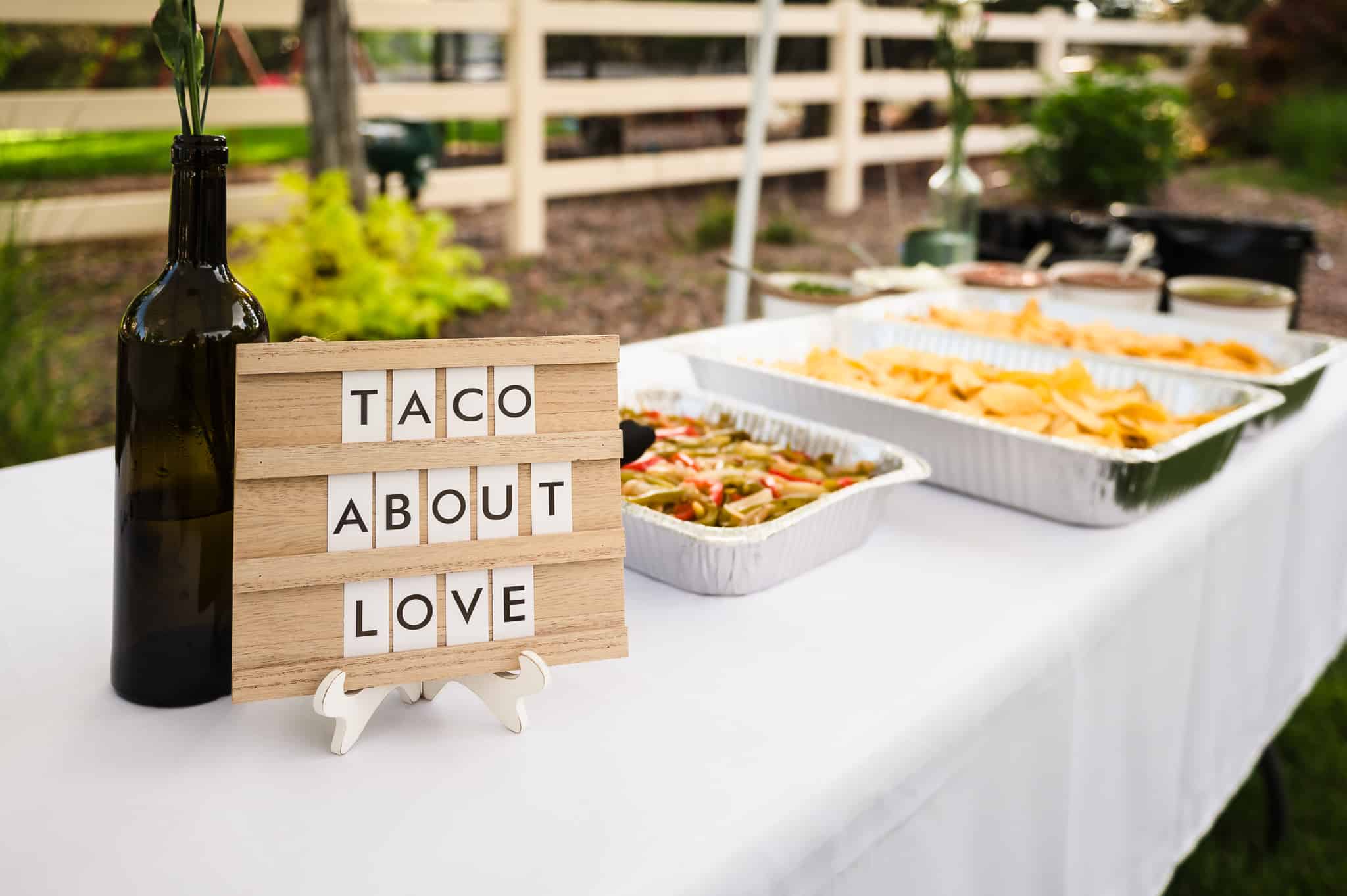 A sign reads "Taco about love" on a wedding buffet table.
