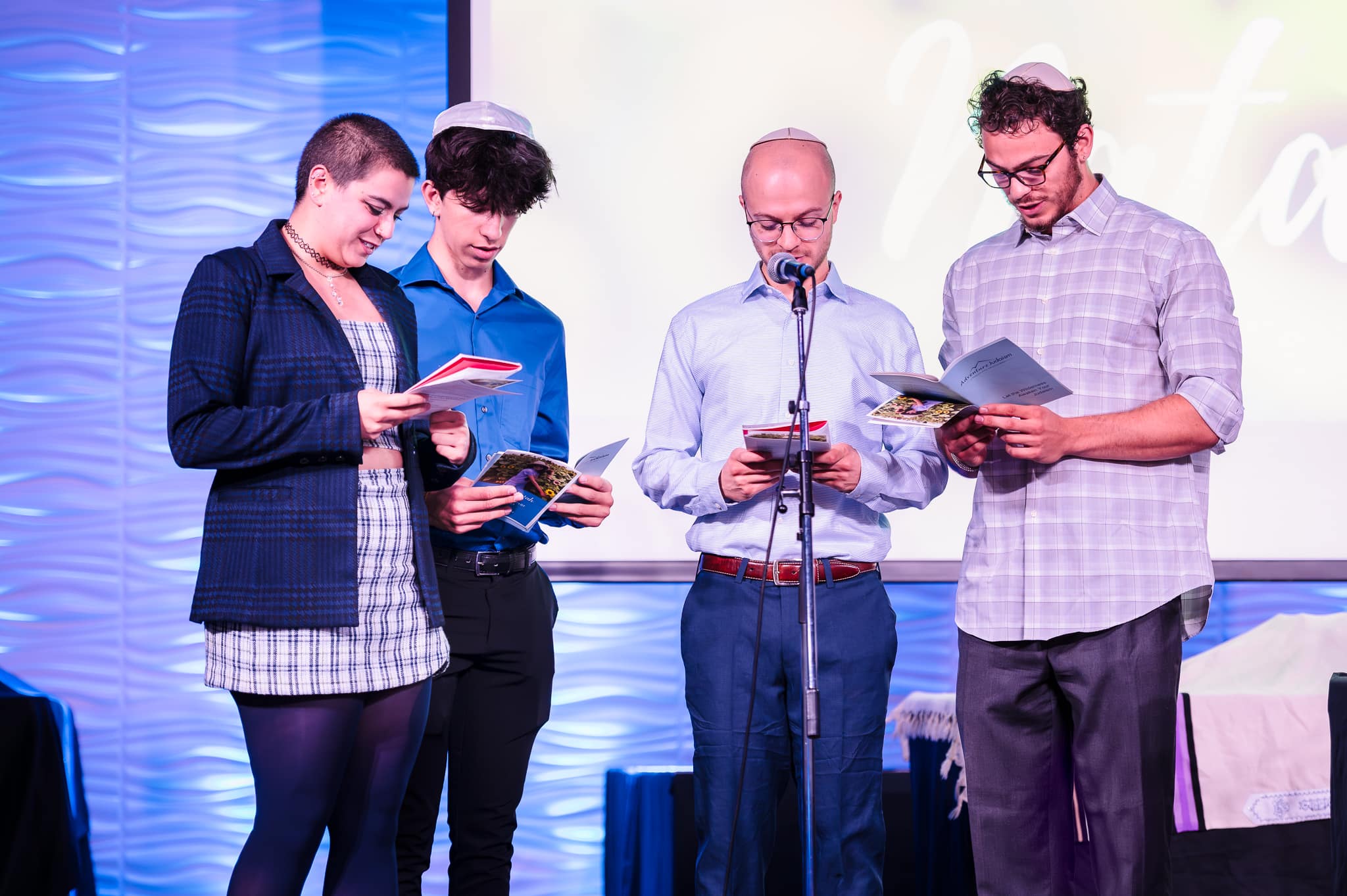 Several cousins at the front of the congregation take turns reading during a mitzvah service.