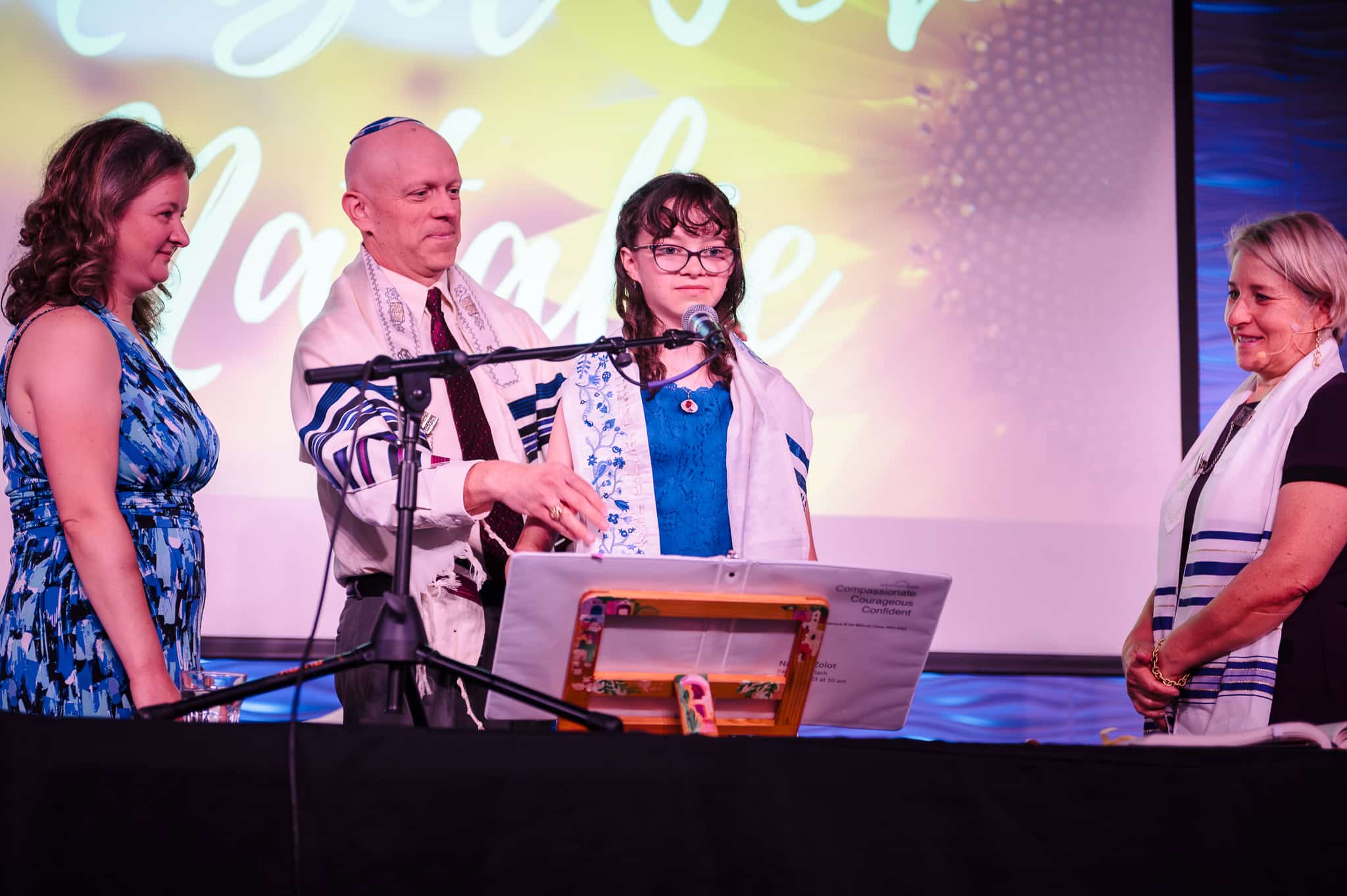 A mother and father present a tallit or prayer shawl to their daughter.