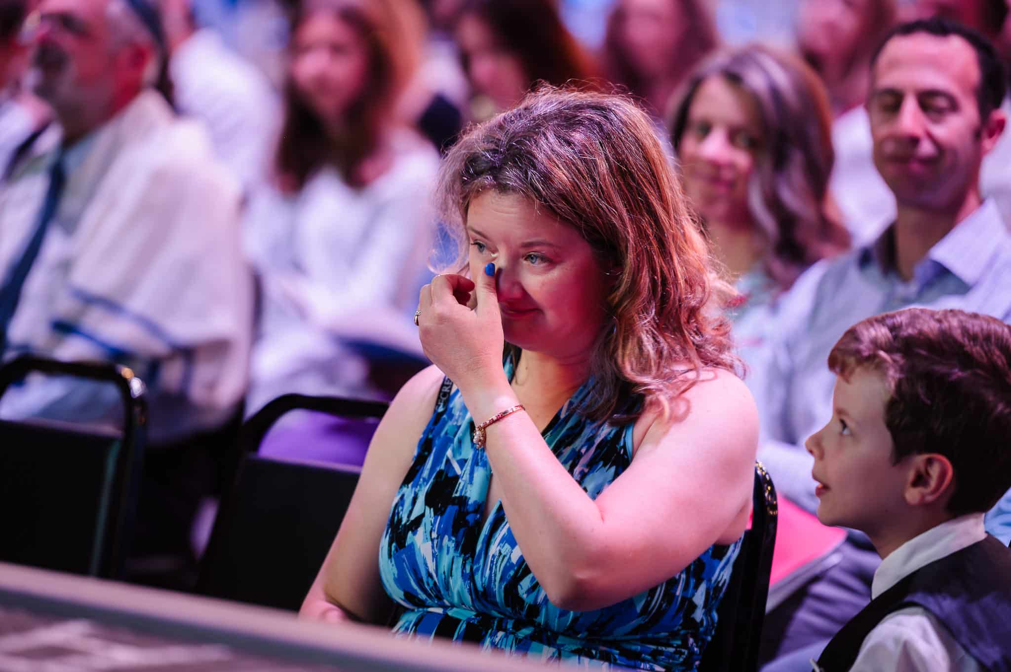 A mother wipes tears from her eyes during a mitzvah service.