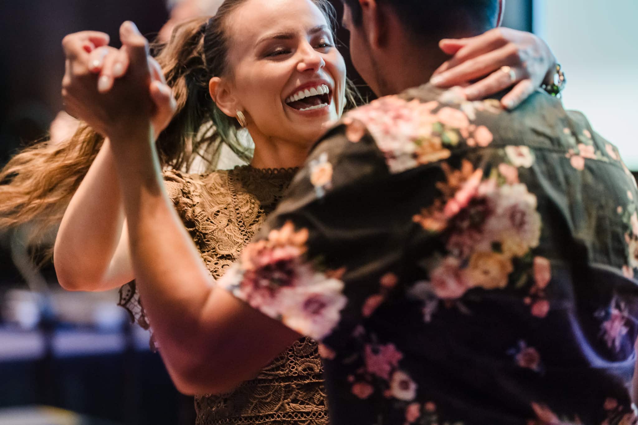 A woman smiles broadly as her partner moves her across the dance floor at the Ritz Carlton.