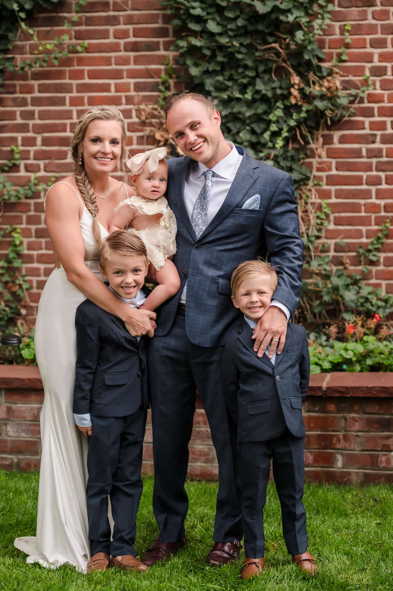 A young baby girl held in the arms of her mother, her father, and two brothers pose for a photo during their 10-year wedding vow renewal celebration.