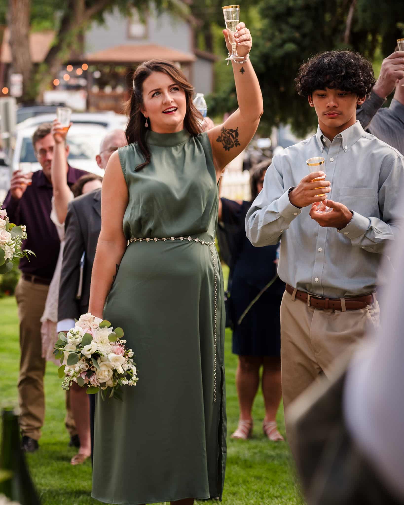 A woman raises her glass to the side of her face during the toast following a wedding.