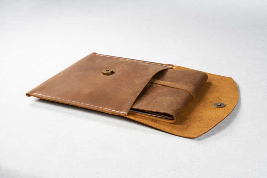 Open side view of a rustic album sliding out of an envelope-style leather wrap.