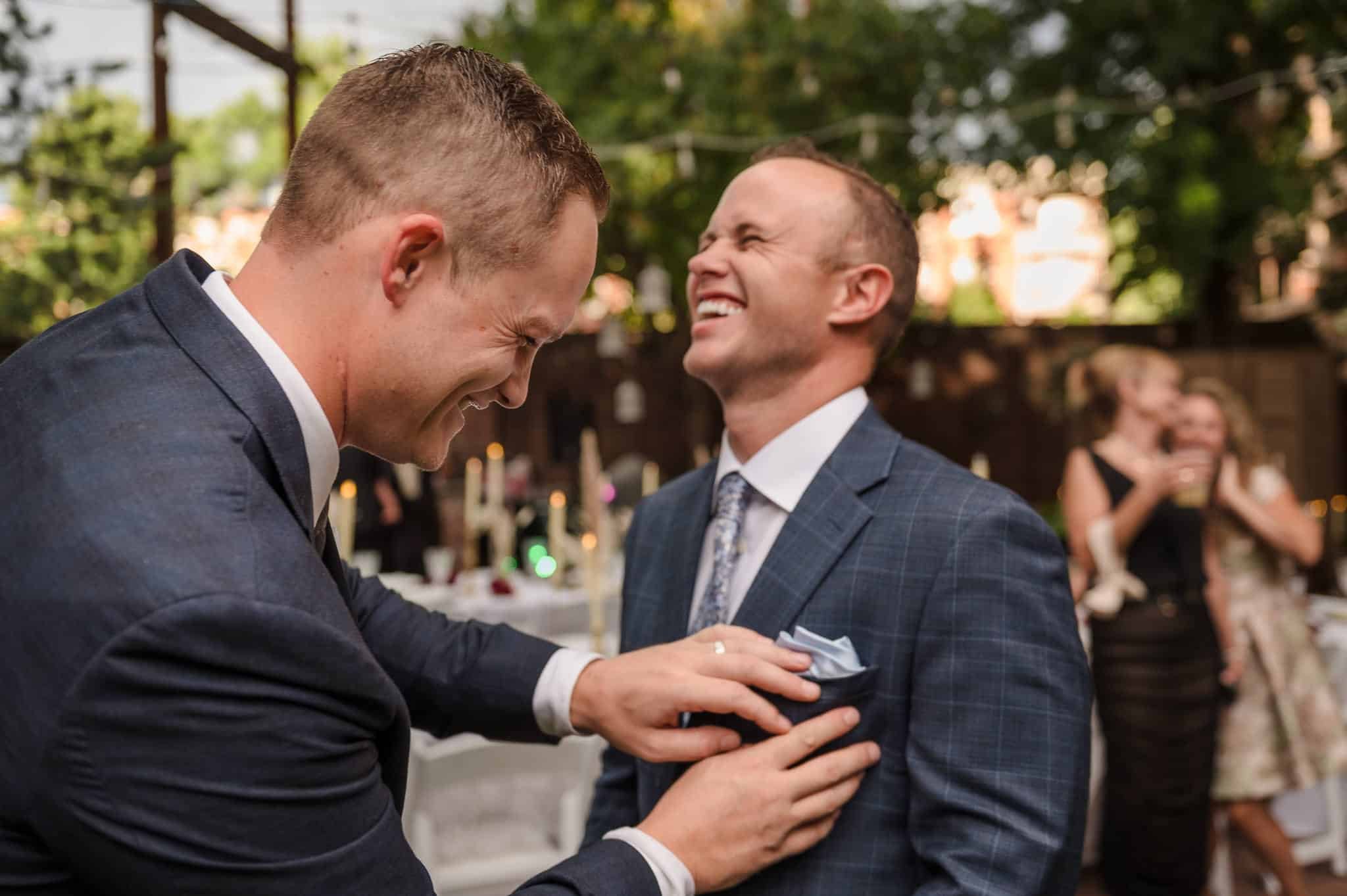 A friend of the groom helps adjust his pocket square.