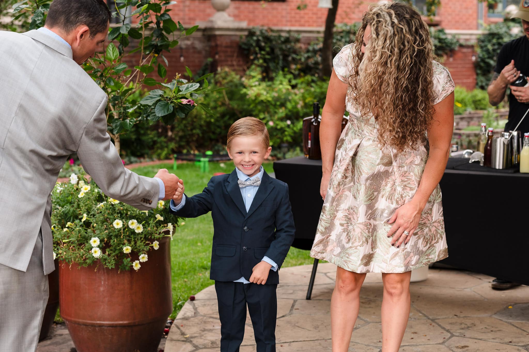 A young boy ready to stand up in a wedding gives a guest a fist bump.
