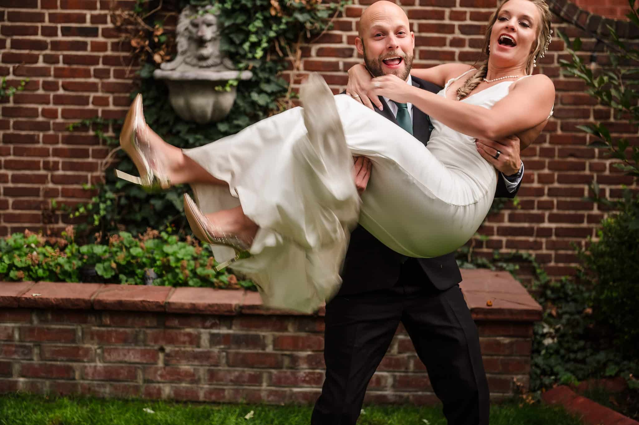 The twin brother of the bride playfully lifts her up in his arms and starts to carry her away.