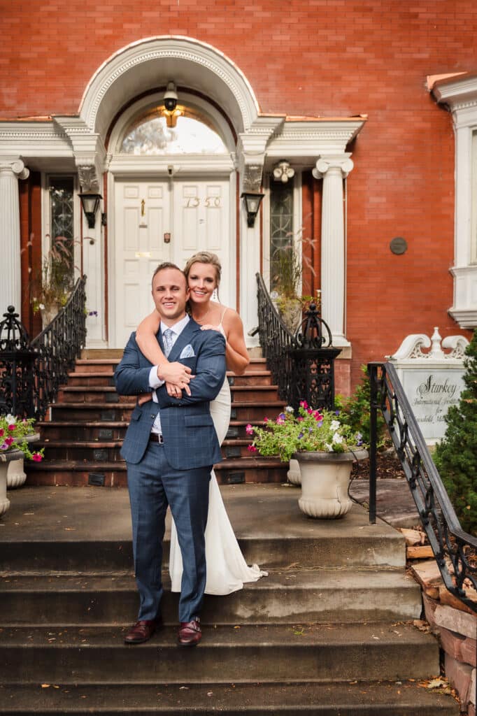 A recently married man and woman stand on the front steps of the Starkey Mansion following their 10-year vow renewal celebration.